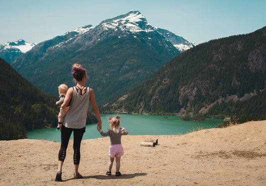 mom with 2 kids standing on sandy beach overlooking mountains