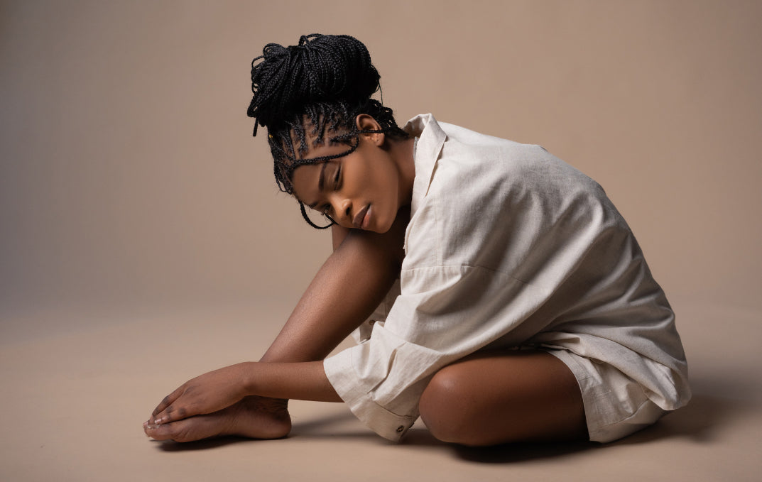 Woman with sensitive skin sitting calmly in a white shirt against a neutral background, representing gentle skincare for eczema-prone skin