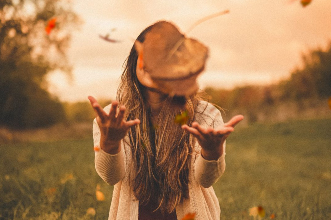 Woman smiling and tossing autumn leaves in a field