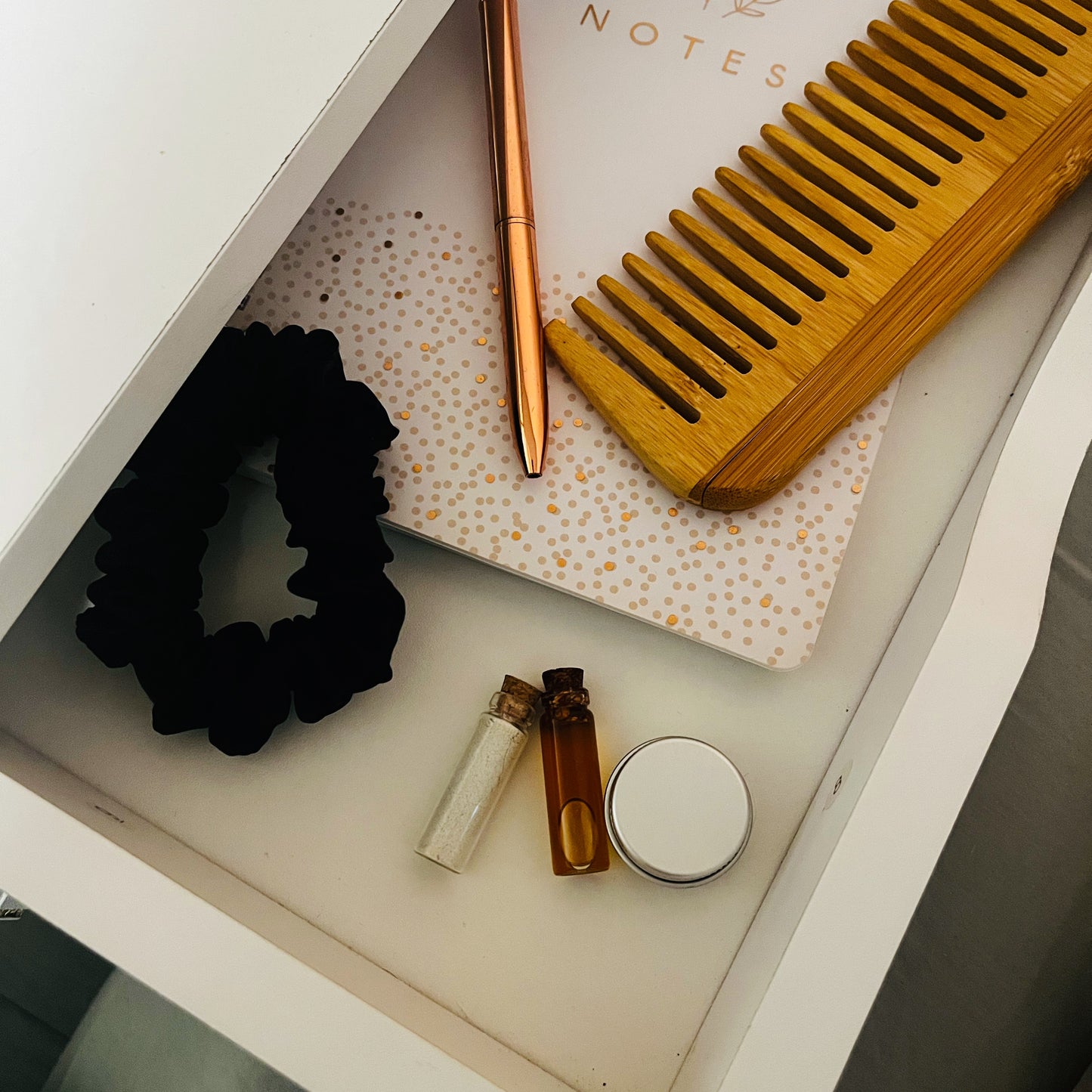 demulcere skincare sample set inside small drawer with a pen, comb and scrunchie on a white surface.