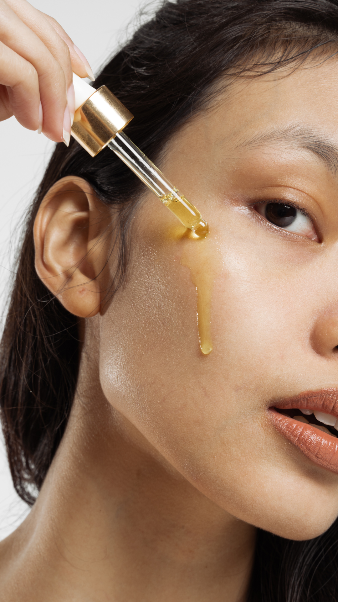 Person applying a dropper of oil to their face